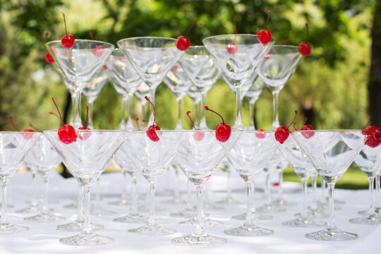 Close-up Of The Champagne Pyramid With A Red Cherry At The Top Of Each GlassGlass Goblets. Pyramid Of Champagne. A Celebratory Drink. Decorations For The Banquet.