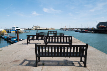 Wooden benches in the Royal Harbour, Ramsgate, looking out towards the lighthouse and an end of pier restaurant