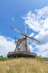 Fototapeta na wymiar Windmill in Hessenpark, a tourist attraction with architecture of ancient towns in Germany, blue sky with white coulds, historic and pitoresque picture