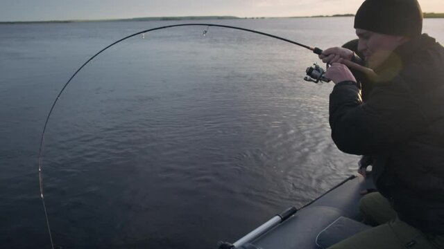 Friends fishing. Two amateur anglers fishing from the boat and fighting with trophy fish