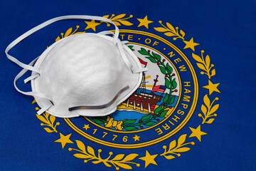 New Hampshire state flag and N95 face mask. Concept of state and local government face covering...