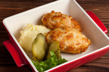 chicken cutlets with mashed potatoes and cucumbers on a wooden background