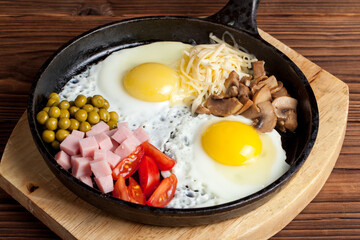 frying pan with fried eggs on a wooden background