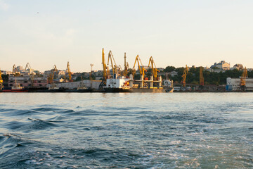 Fototapeta premium Portal cranes in the evening port in Odessa, Black Sea. Waves at sea