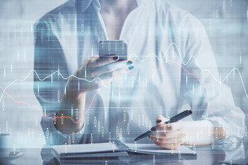 Double exposure of forex chart sketch hologram and woman holding and using a mobile device. Financial market concept.