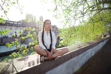 a young woman sits on the Bank of the river