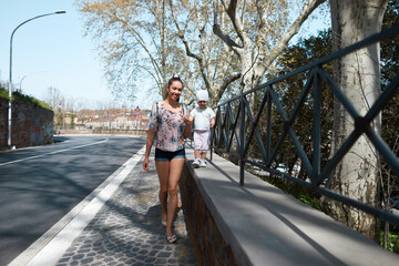 young woman and her daughter walking on the road
