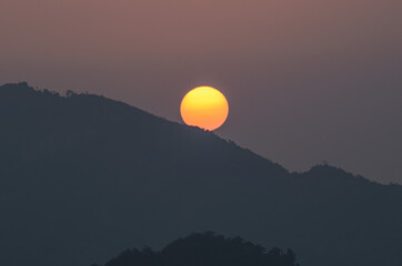 Amanecer en las montañas con el sol naranja gigante. el sol nace tras las montañas en el amanecer.