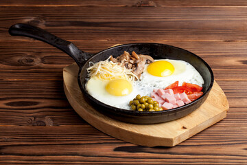 frying pan with fried eggs on a wooden background	
