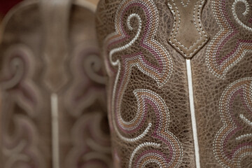 Selective focus closeup of decorative stitching on a pair of brown leather western boots.