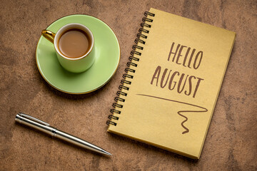 Hello August welcome note  - handwriting in a spiral sketchbook with a cup of coffee, greeting card and calendar concept