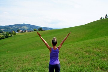 Young girl doing yoga on the green meadow