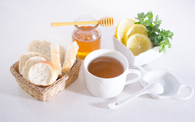 Healthy breakfast with a cup of tea, bread, honey, lemon and mint.