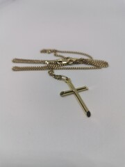 Golden cross necklace, Christian jewelry on a grey background.