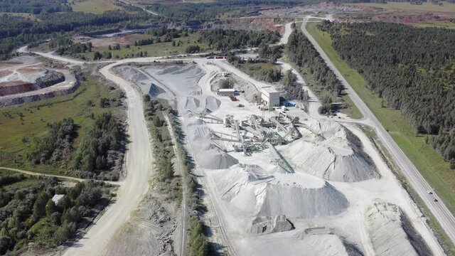 Aerial video view of mining quarry. Stone crushing machine crushes rock into gravel.