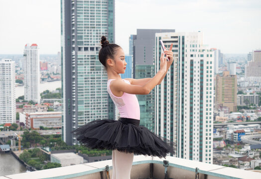 Ballet girl students are holding a smartphone in hand and taking a picture yourself photo on a high-rise building.