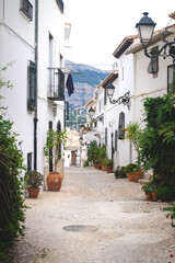 Alley with flower pots in the old town of Altea with view on mountains, Costa Blanca, Spain