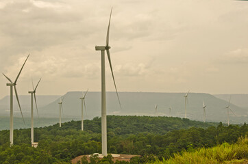 Big wind turbines in the green forest on the mountain