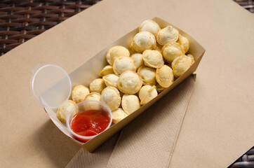 fried dumplings with red sauce in a cardboard box