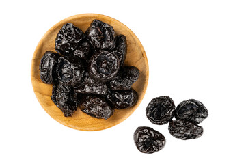Top view of dried pitted prunes in wooden plate and prunes on the floor over white background.