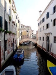narrow venetian canal with boats and bridge