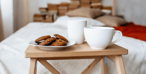 Breakfast in bed. Hot coffee with oatmeal cookies with chocolate on a wooden tray.