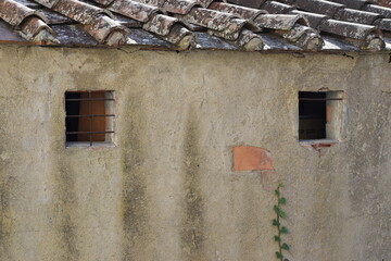 The abstract poking face on the aged medieval wall in Tuscany Italy