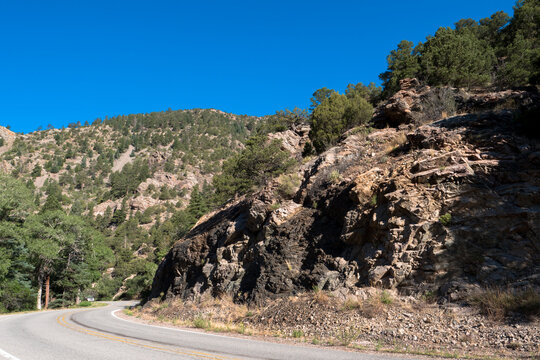 Car on a curvy road through forested cliffs in New Mexico’s Cimarron Canyon State Park in the Sangre de Cristo Range of the Rocky Mountains