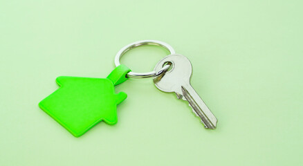 key chain with house symbol and keys on green background,Real estate concept