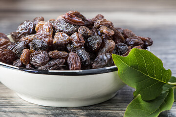Raisins in glass bowl with green leaf on wood. Healthy Food