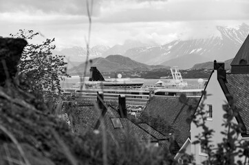 Modern cruiseship or cruise ship liner calls to port of Alesund in Norway with beautiful nature...