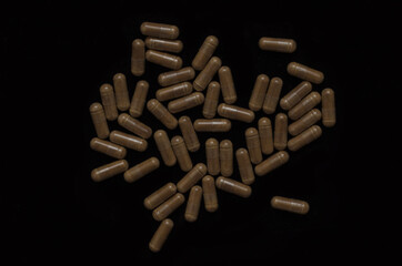 Maca dietary supplement for athletes in capsules on a black background