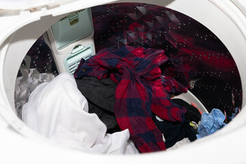 縦型の使い古された洗濯機の中で絡み合う服