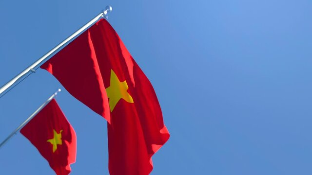 The national flag of Vietnam is flying in the wind against a blue sky