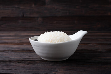 Bowl of boiled rice served on wooden table,
