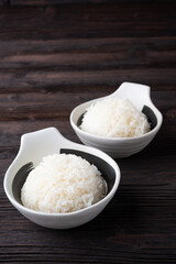 Bowl of boiled rice served on wooden table,
