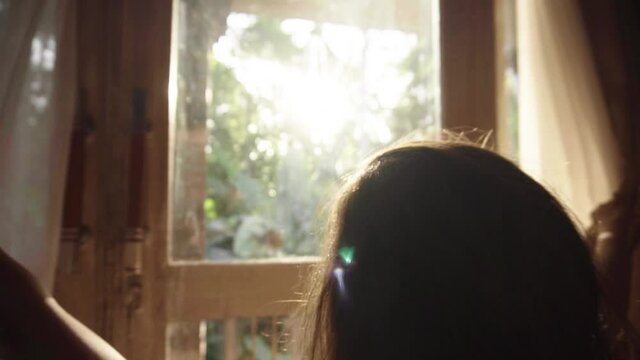 Slow motion of woman opening curtains and look through window in the morning