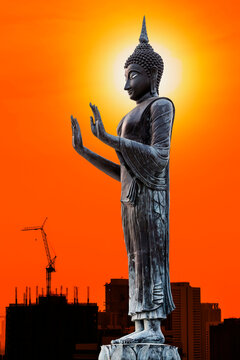 The Statue of Buddha on silhouette of construction crane on sunset sky background.