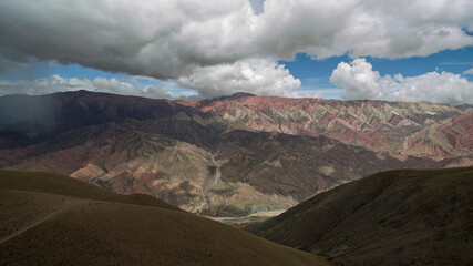 Fototapeta premium Hiking. Path across the golden meadow, valley and mountains. Aerial view of the popular landmark mountain Hornocal. Its beautiful texture and colorful rocks under a dramatic sky. 