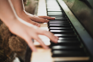 Fototapeta premium The girl plays the piano, photo in large plan. Background image of an old piano. Classic keys, music 