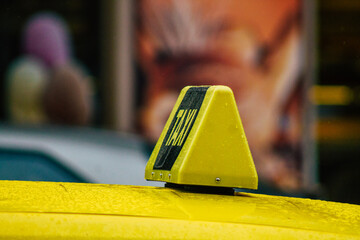 View of a traditional yellow Hungarian taxi for passengers driving under the rain through the streets of Budapest the capital of Hungary 

