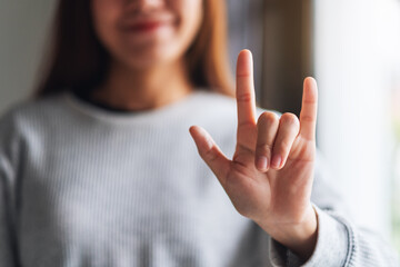 Closeup image of a woman making and showing love hand sign with feeling happy