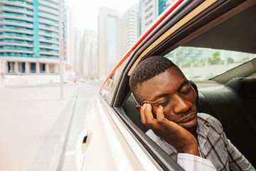 exhausted young african man sleeping in taxi