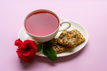 Cup of fruit tea with cookies and red rose
