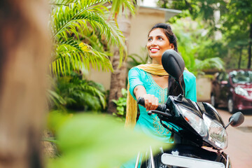 Pretty Indian woman riding a scooter