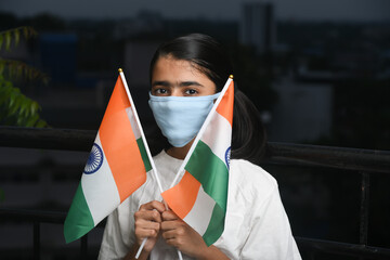 Corona virus pandemic or COVID-19 in India. Young Indian girl holding Indian flag wearing safety mask Kerala, India.