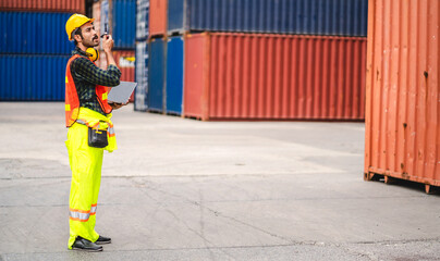 Professional engineer container cargo foreman in helmets working standing and using walkie talkie checking stock into container for loading.logistic and business export