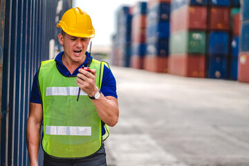 Professional engineer container cargo foreman in helmets working standing and using walkie talkie checking stock into container for loading.logistic and business export