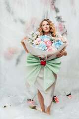 Beautiful girl with beautiful makeup on her face and hairstyle with a large luxurious bouquet of flowers, advertising for cosmetologists and florists with decorators