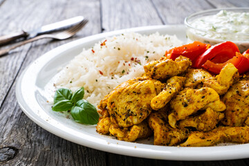 Chicken meat with rice and vegetables on wooden table
